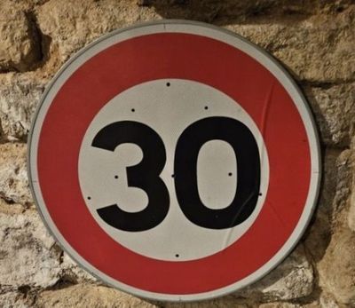 une photo d'un panneau de limitation de vitesse sur un mur en pierre