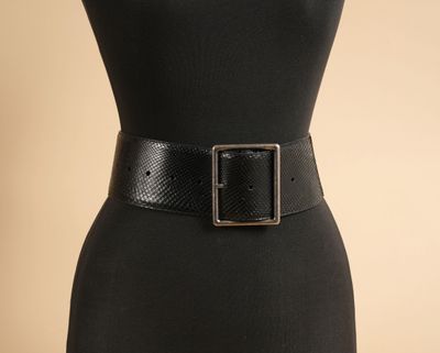 une femme vêtue d'une robe noire et d'une ceinture noire à boucle argentée