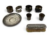 an assortment of metal objects including a brush, bowl, and other items