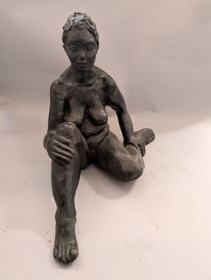 statue représentant un garçon assis par terre, les mains posées sur les genoux