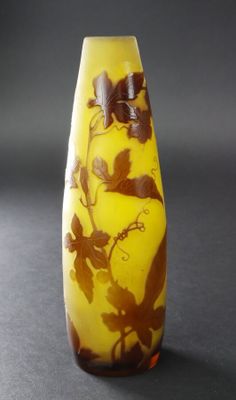 un vase jaune orné de fleurs marron, posé sur une table