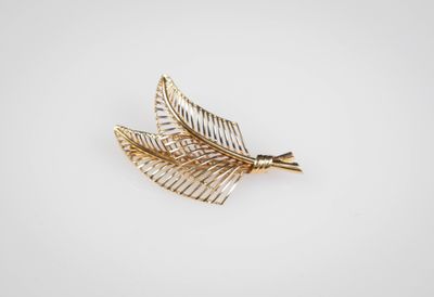 un gros plan d'une broche en feuille d'or sur fond blanc