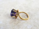 an image of a gold ring with a purple stone in it