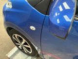 a blue car parked in a parking space with its door open