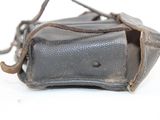 a small black bag with a brown handle on a white surface