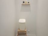 a toilet in the corner of a bathroom with a shelf on the wall