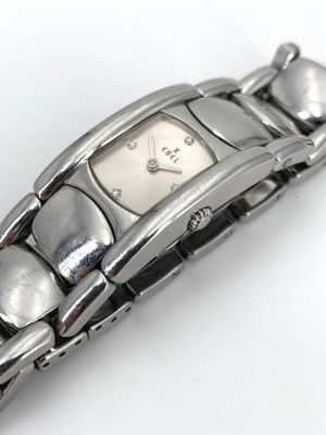 une montre en argent posée sur une surface blanche