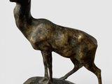 statue en bronze représentant un cerf debout sur un rocher, sur fond blanc