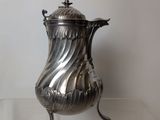a silver vase that is on a glass table