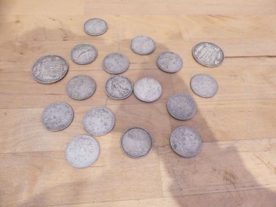un tas de pièces de monnaie par terre, à côté de l'ombre d'une personne