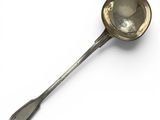 an antique silver spoon with a spoon handle on a white surface