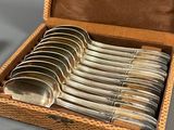 a box of silver spoons sitting on a table next to a pair of silver spoons