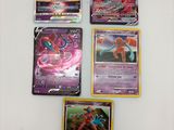 quatre cartes Pokémon différentes sont posées sur une surface blanche