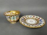 a small cup and saucer with a gold rim