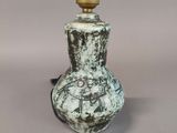 a white and black vase with a light on top of it