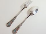 two spoons and a fork on a white table