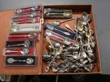 une boîte remplie de cuillères en argent et des cuillères posées sur une table