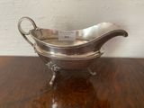 a silver gravy dish sitting on a wooden table