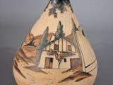 a small vase with a painting on it sitting on a table