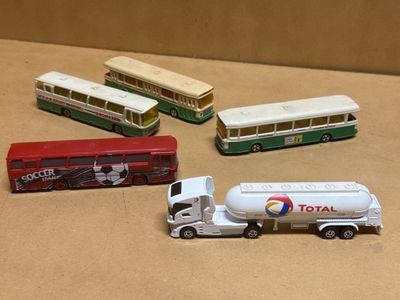 four toy buses and a tanker truck on a table