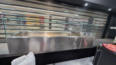 un grand comptoir en acier inoxydable dans un magasin doté d'une vitrine