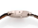 a close up of a watch on a white surface with a brown strap