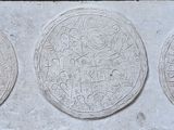 trois plaques ovales en pierre ornées de motifs, fixées sur un mur en pierre