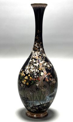un vase noir orné de fleurs, posé sur une table