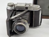 an old camera sitting on a table next to a picture frame
