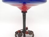 un bol en verre bleu et rouge posé sur un socle en métal