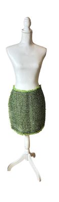 a mannequin with a green skirt on a white stand