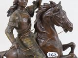 bronze statue of a woman riding a horse holding a flag