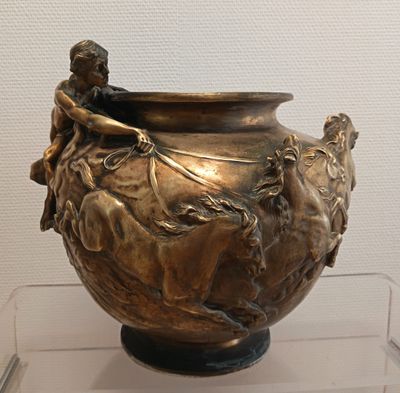 un vase en bronze sur lequel est représenté un homme à cheval