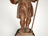 an old bronze statue of a boy with a cane and a hat
