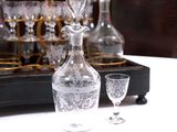 a bottle and a glass on a table next to a tray of wine glasses