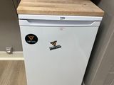 un petit réfrigérateur blanc dans le coin d'une pièce