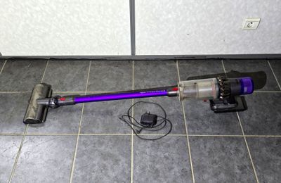 a purple corded vacuum on the floor next to a wall