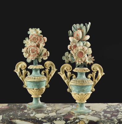 Deux vases remplis de fleurs sont posés sur une table, sur fond noir.