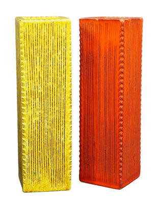 pair of orange and yellow vases sitting side by side on a white surface