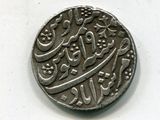 une vieille pièce de monnaie portant une inscription en arabe, posée sur une surface blanche