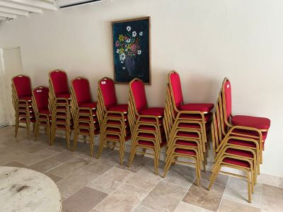de nombreuses chaises rouges alignées dans une pièce où est accroché un tableau au mur