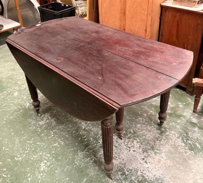 Table à volets en bois ciré, pieds cannelés.