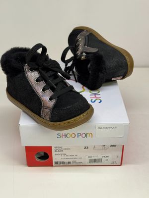 une paire de chaussures de bébé noires et argentées posées sur une boîte