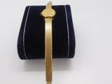 a close up of a gold bracelet on a blue velvet case