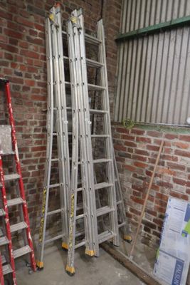 plusieurs échelles appuyées contre un mur de briques dans une pièce