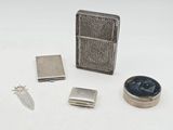 un briquet, un étui à briquet, un couteau et d'autres objets posés sur une surface blanche