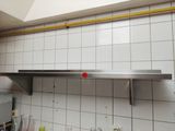 une photo d'une cuisine avec une étagère en acier inoxydable