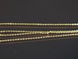 un gros plan d'un collier en or avec une chaîne, posé sur une surface noire