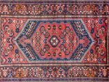 a red and blue rug with an ornate design