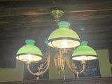 a chandelier with three green lamps hanging from it ' s ceiling